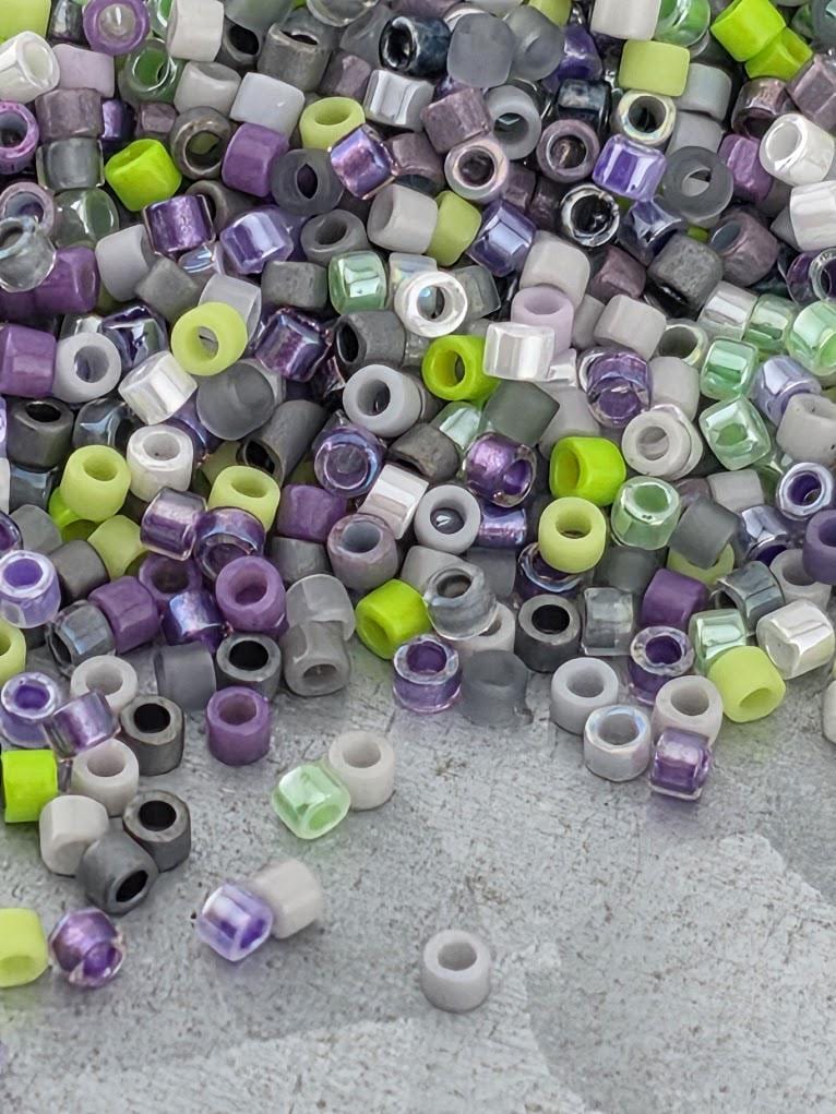 A pile of multicolored beads, including purple, green, and gray, scattered on a surface.