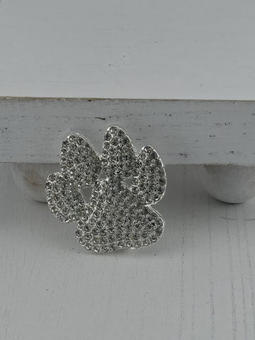 A silver decorative piece with a floral pattern and sparkling crystal elements is displayed against a white wooden background.