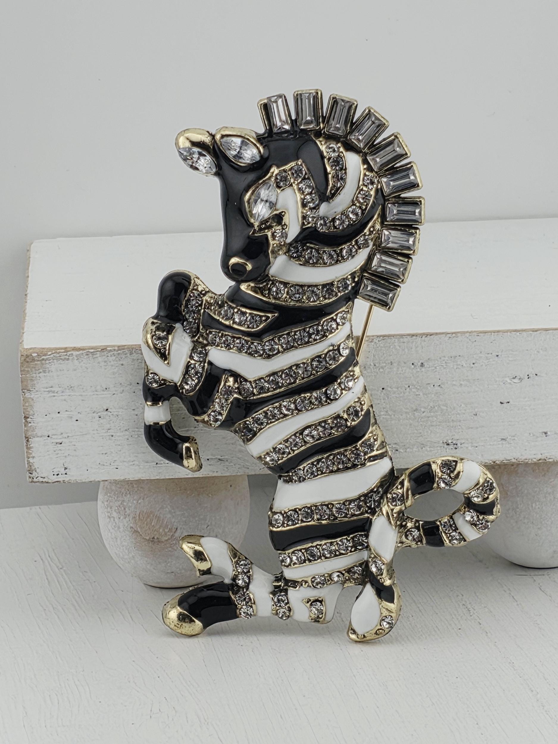 A decorative zebra brooch with black and white stripes and sparkling rhinestones.