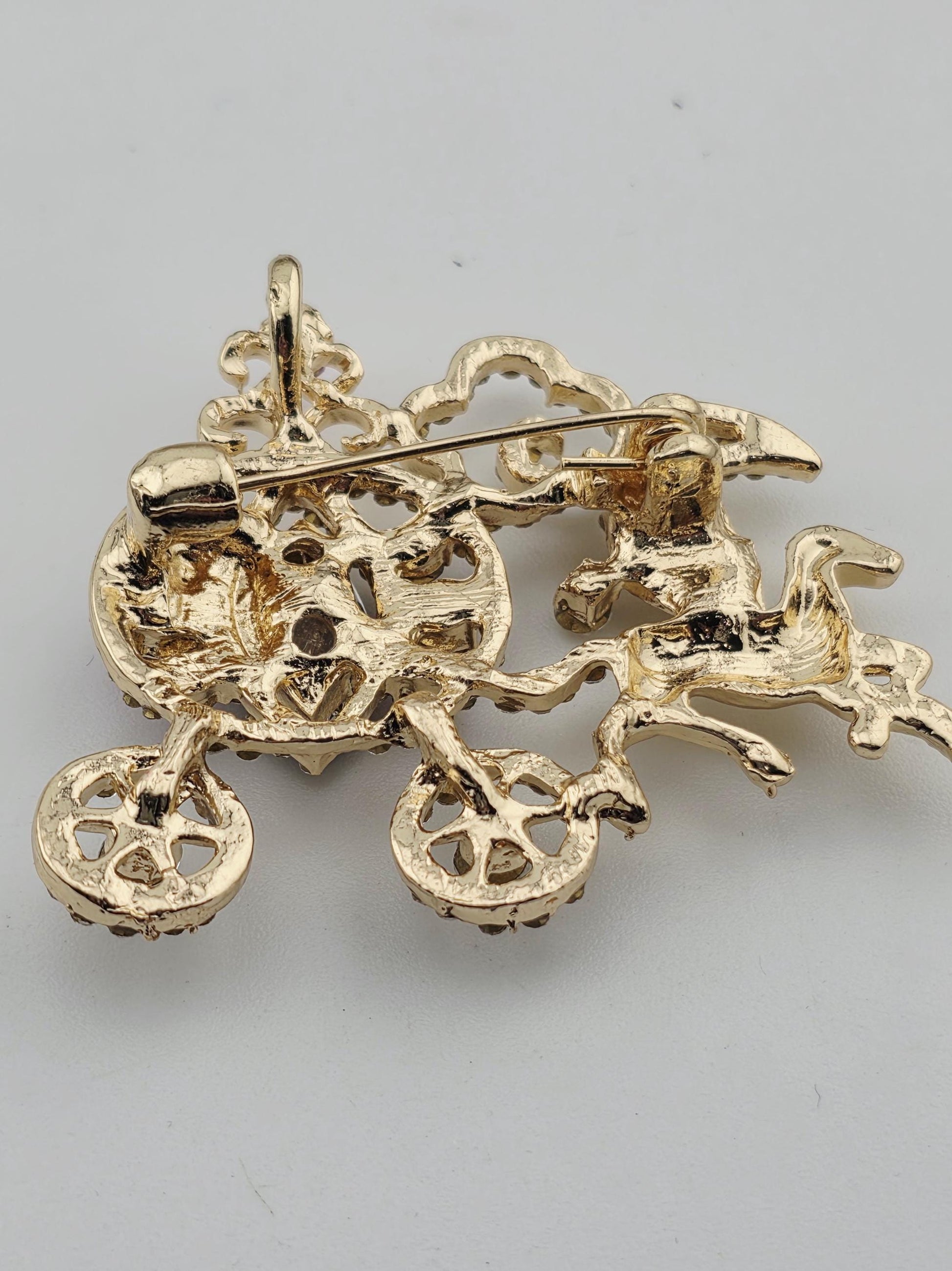 a gold-colored pin with an intricate, sculptural design.