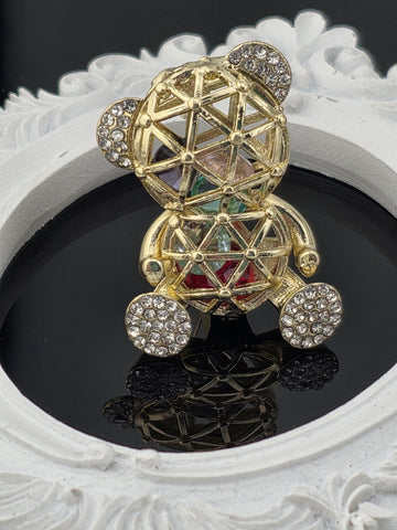 A decorative piece of jewelry with a metallic structure and gemstone elements, including a pendant and a ring.