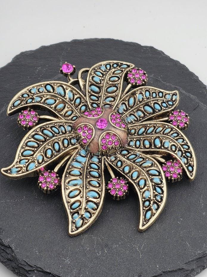 A decorative brooch with a floral design and colorful gemstones.