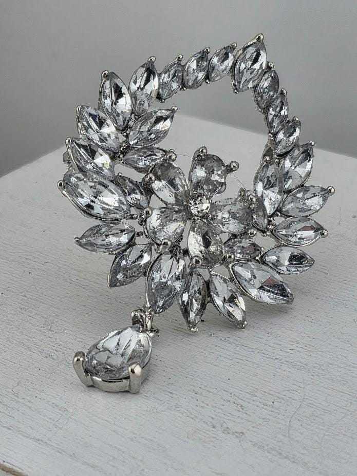 A close-up view of a decorative piece featuring a large, intricate arrangement of clear, sparkling crystals or gemstones set within a frame.