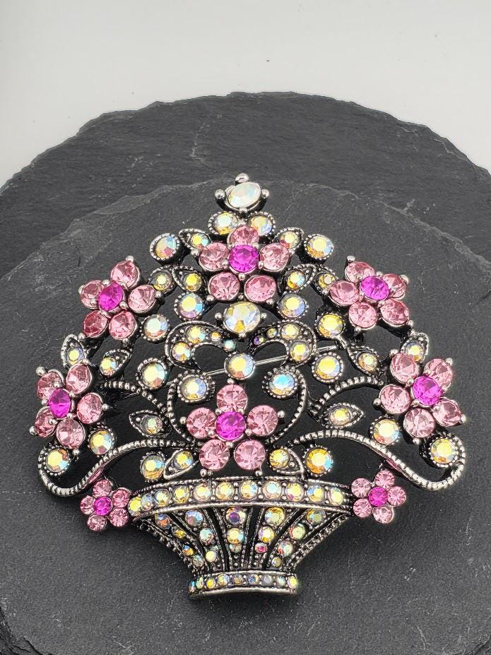 A decorative brooch with a floral design and sparkling rhinestones in various colors, including pink, purple, and blue.
