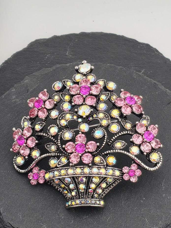 A decorative brooch with a floral design and sparkling rhinestones in various colors, including pink, purple, and blue.