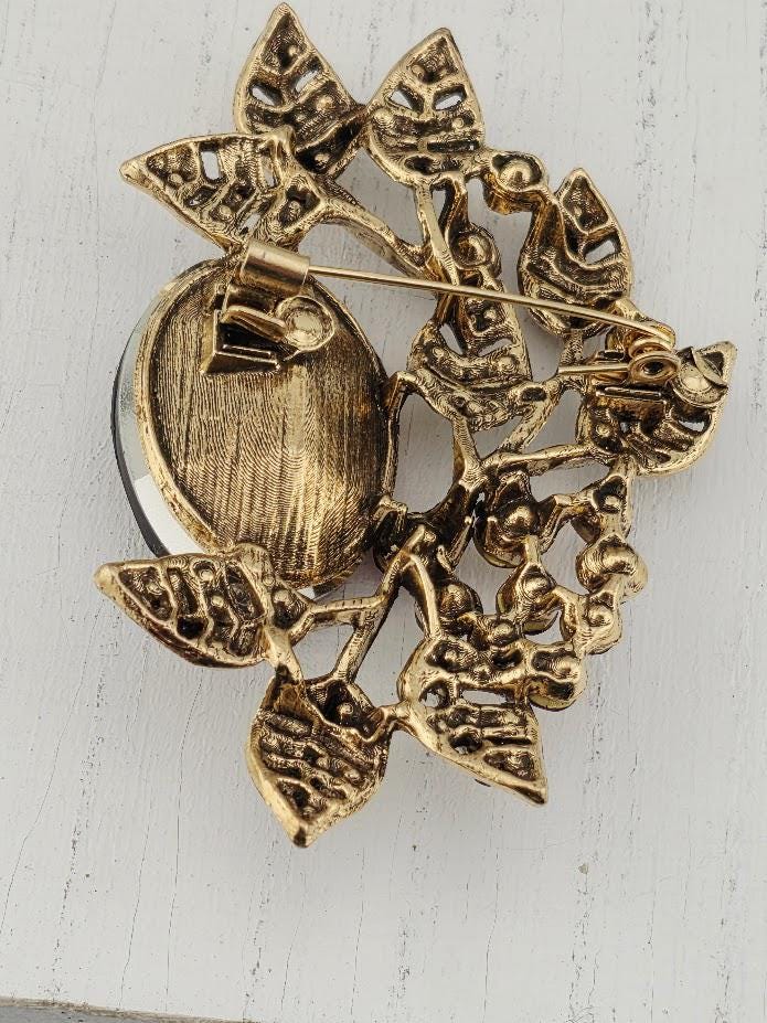 A decorative gold brooch with leaf-like designs and a round center piece.