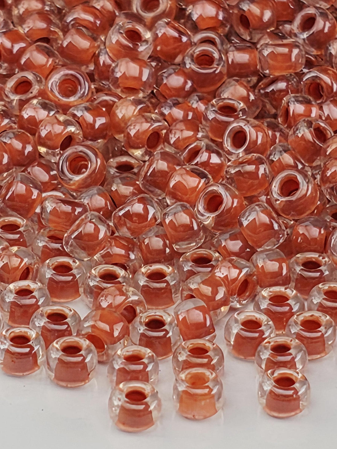 a close-up view of numerous clear and orange-colored beads or beads, possibly made of glass or plastic, scattered across a surface.