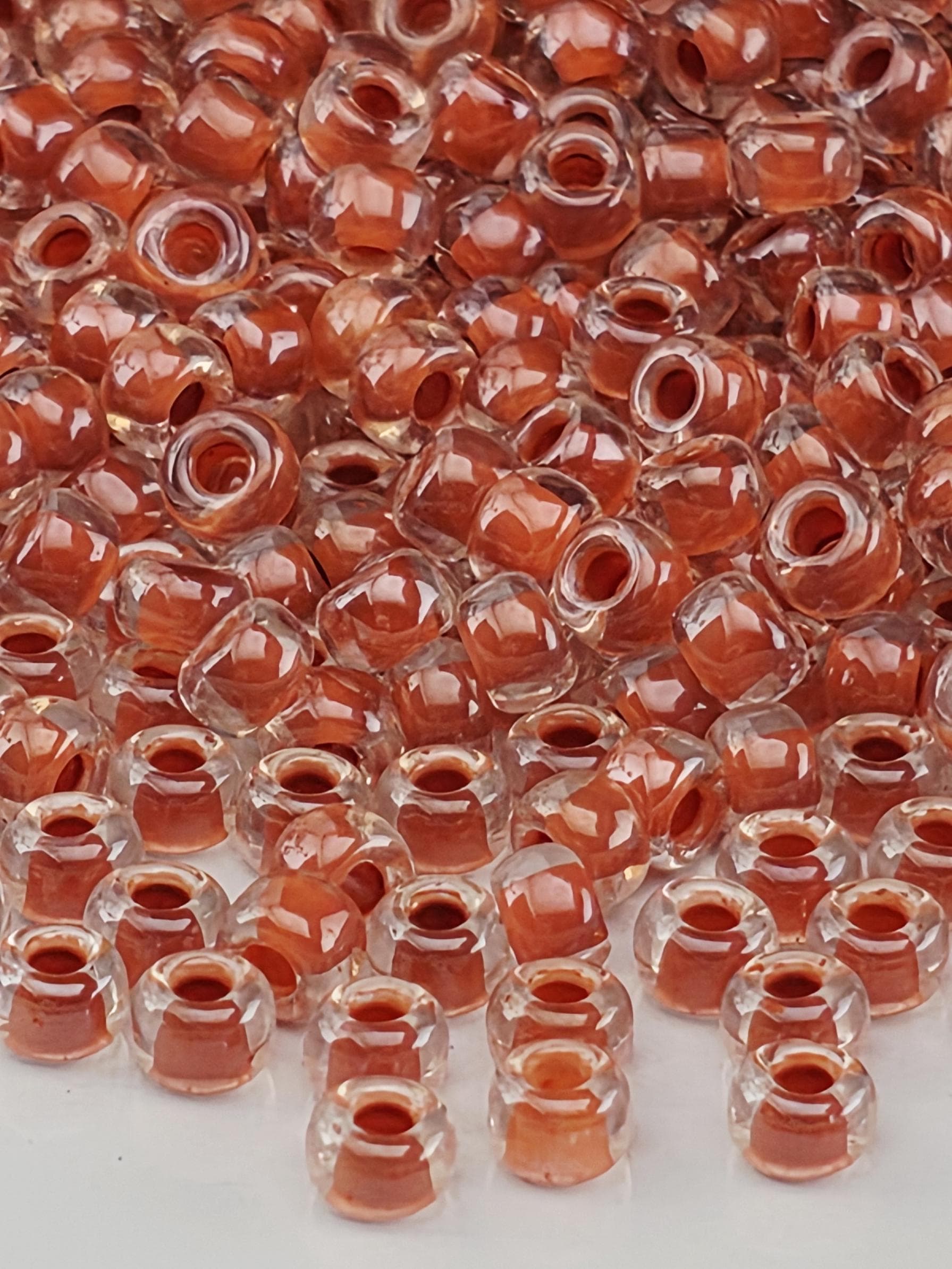 a close-up view of numerous clear and orange-colored beads or beads, possibly made of glass or plastic, scattered across a surface.