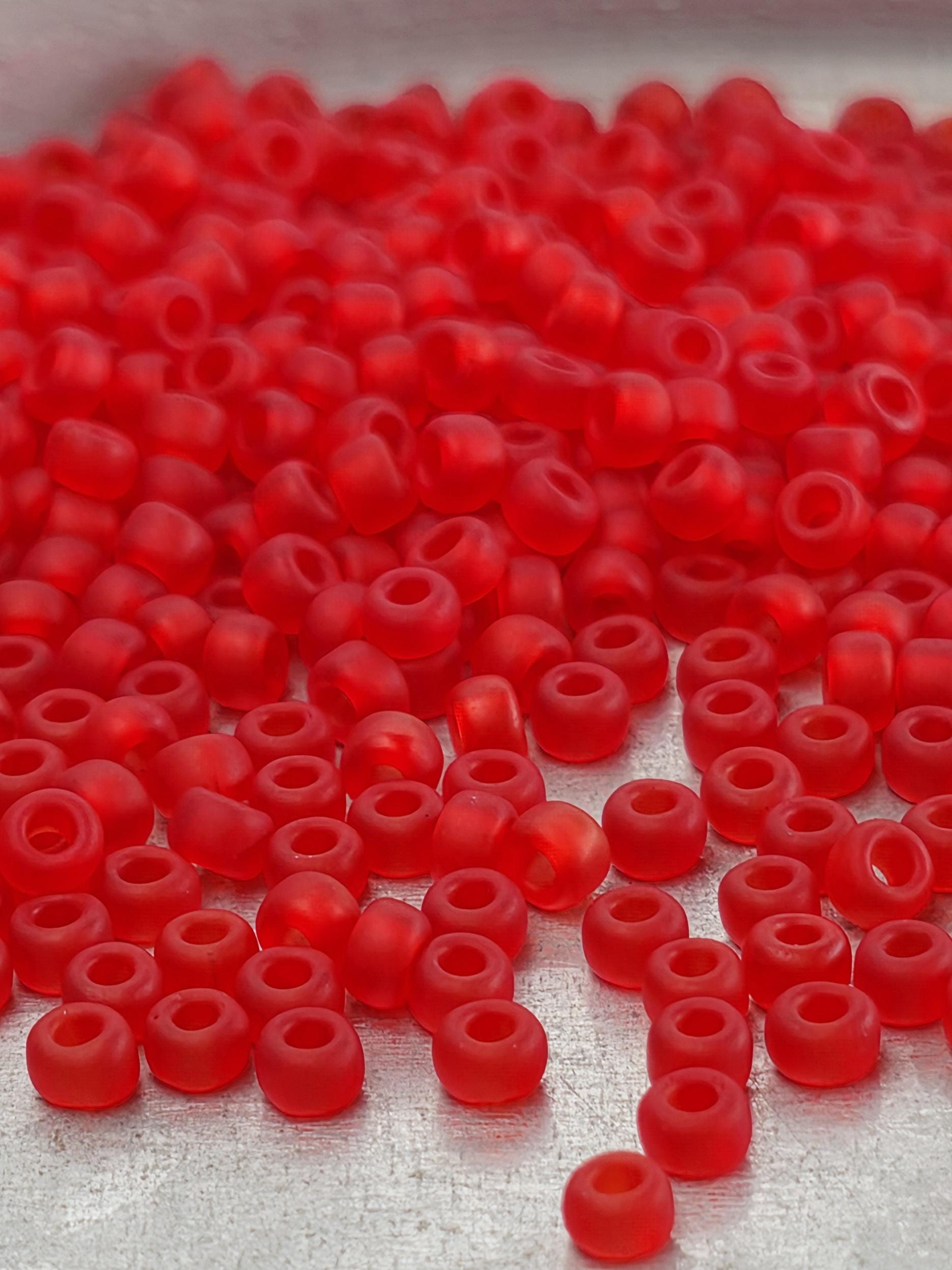 A pile of red glass beads or marbles, scattered and overlapping each other.