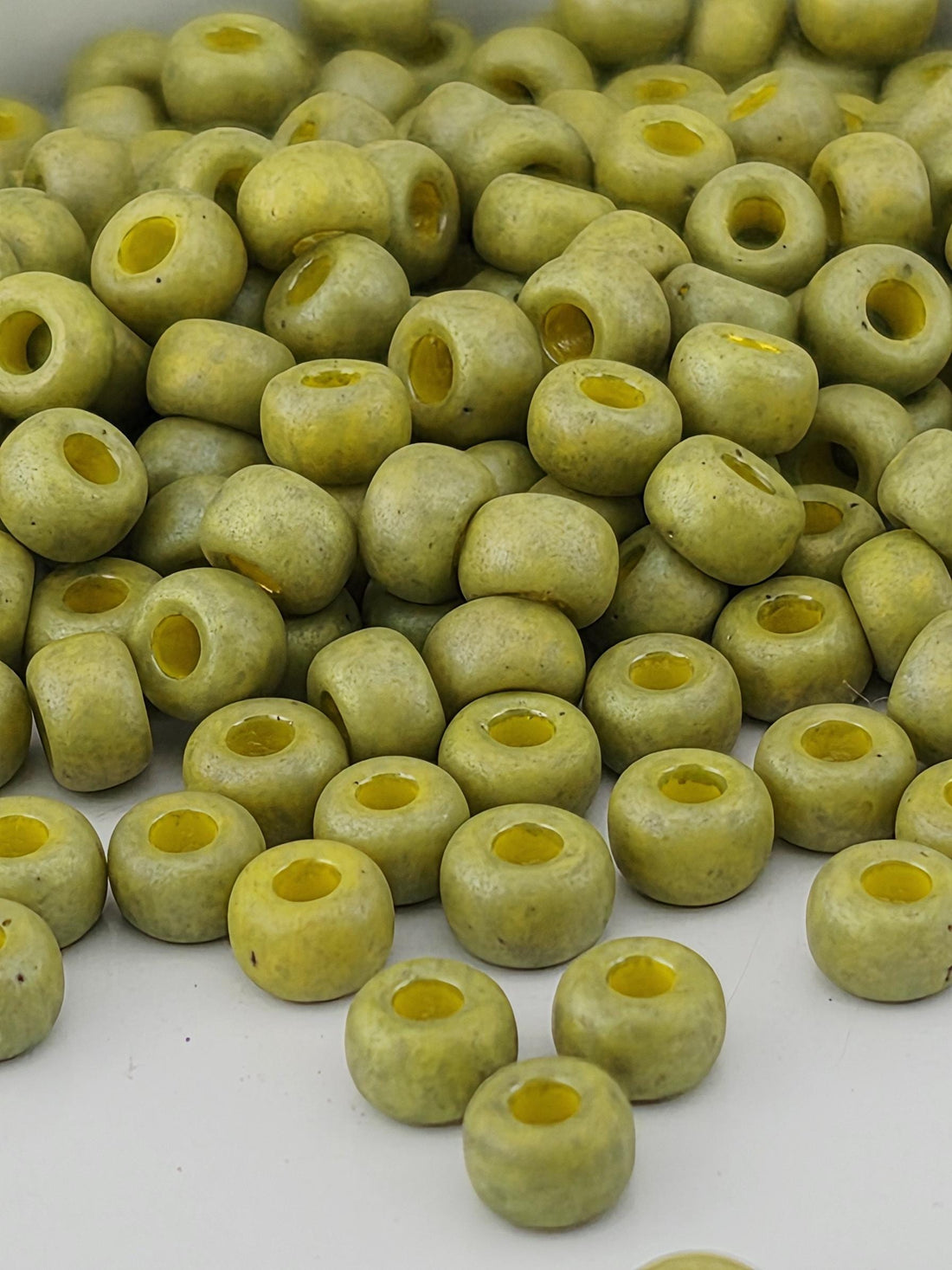 a close-up view of a pile of green beads or objects with yellow centers, arranged in a visually appealing manner.