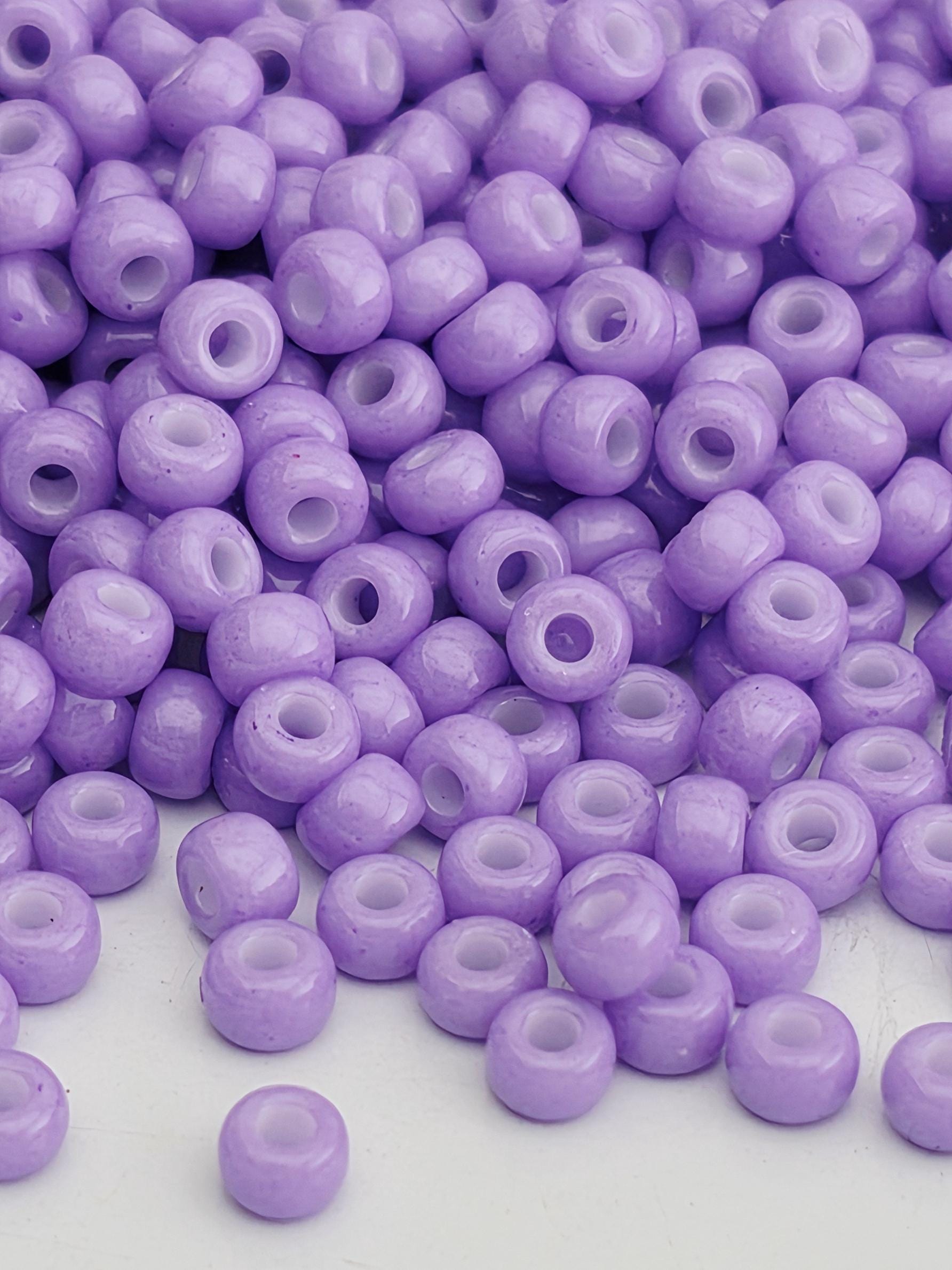 A close-up image of numerous purple beads scattered on a white surface.