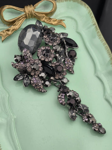 a collection of ornate jewelry, including a large crystal piece and a decorative bow, displayed on a light green tray.