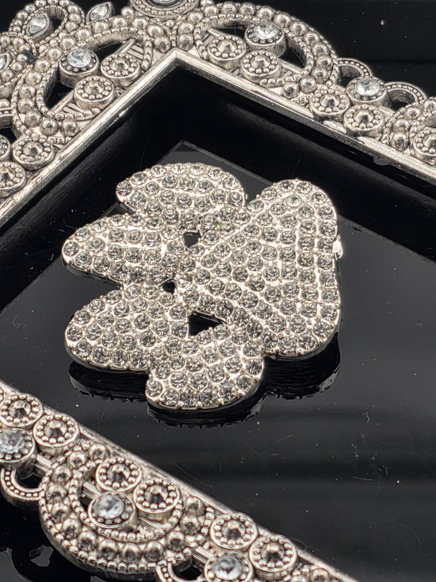 a close-up view of a diamond-encrusted piece of jewelry, possibly a necklace or pendant, set against a black background.