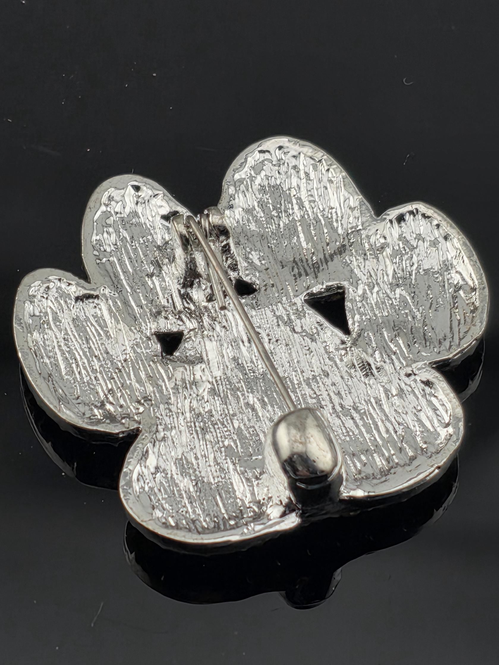 A close-up view of a shiny, metallic pin or brooch with a textured surface.