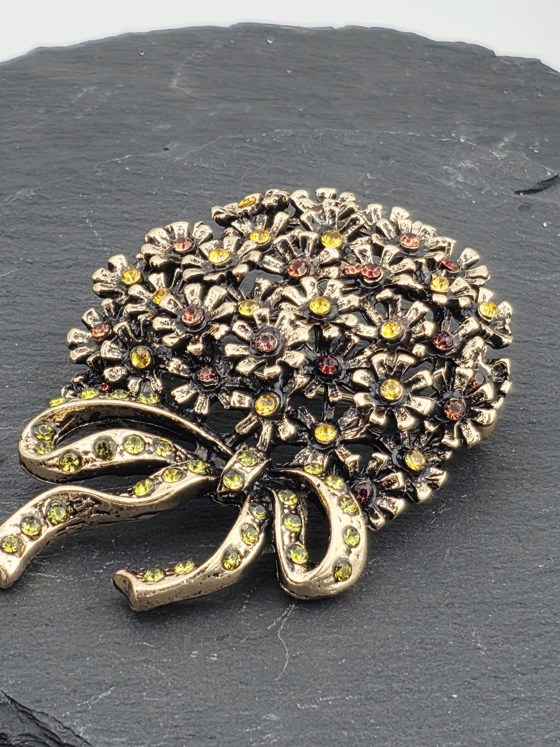 A decorative brooch with a floral design and sparkling gemstones.