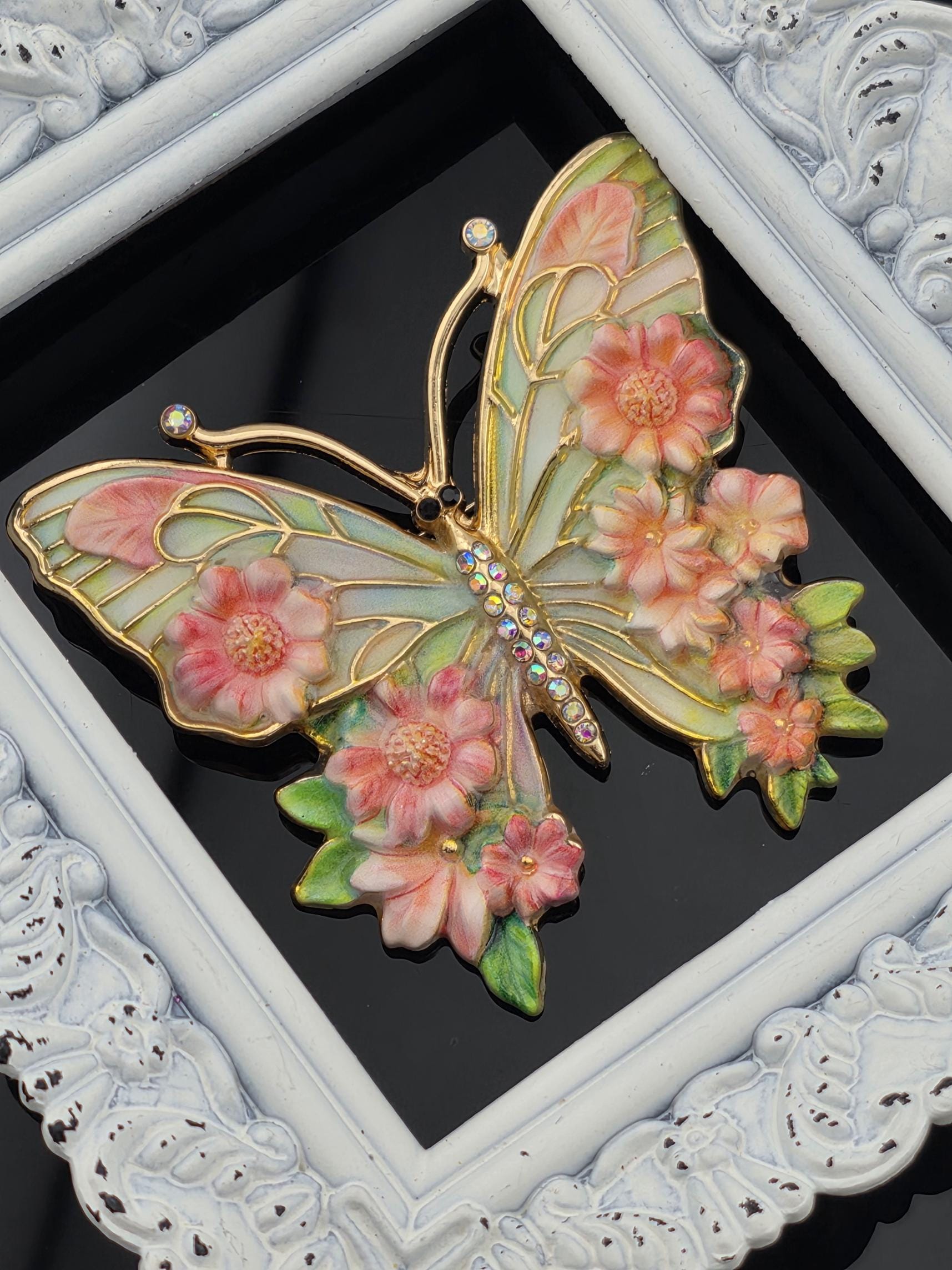 A decorative butterfly with pink flowers is displayed in a white ornate frame.