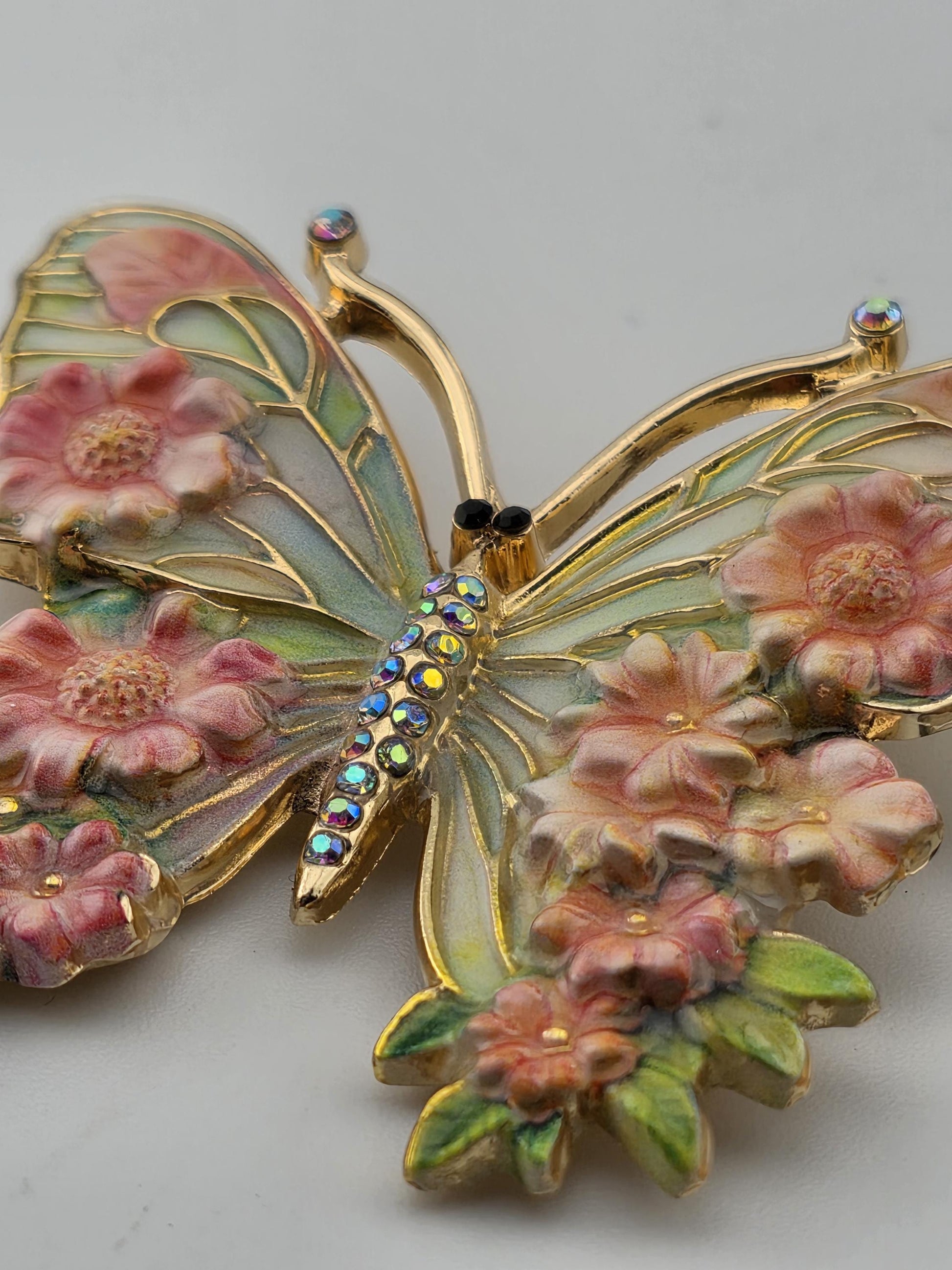 A decorative butterfly brooch with a floral design and sparkling gemstones.