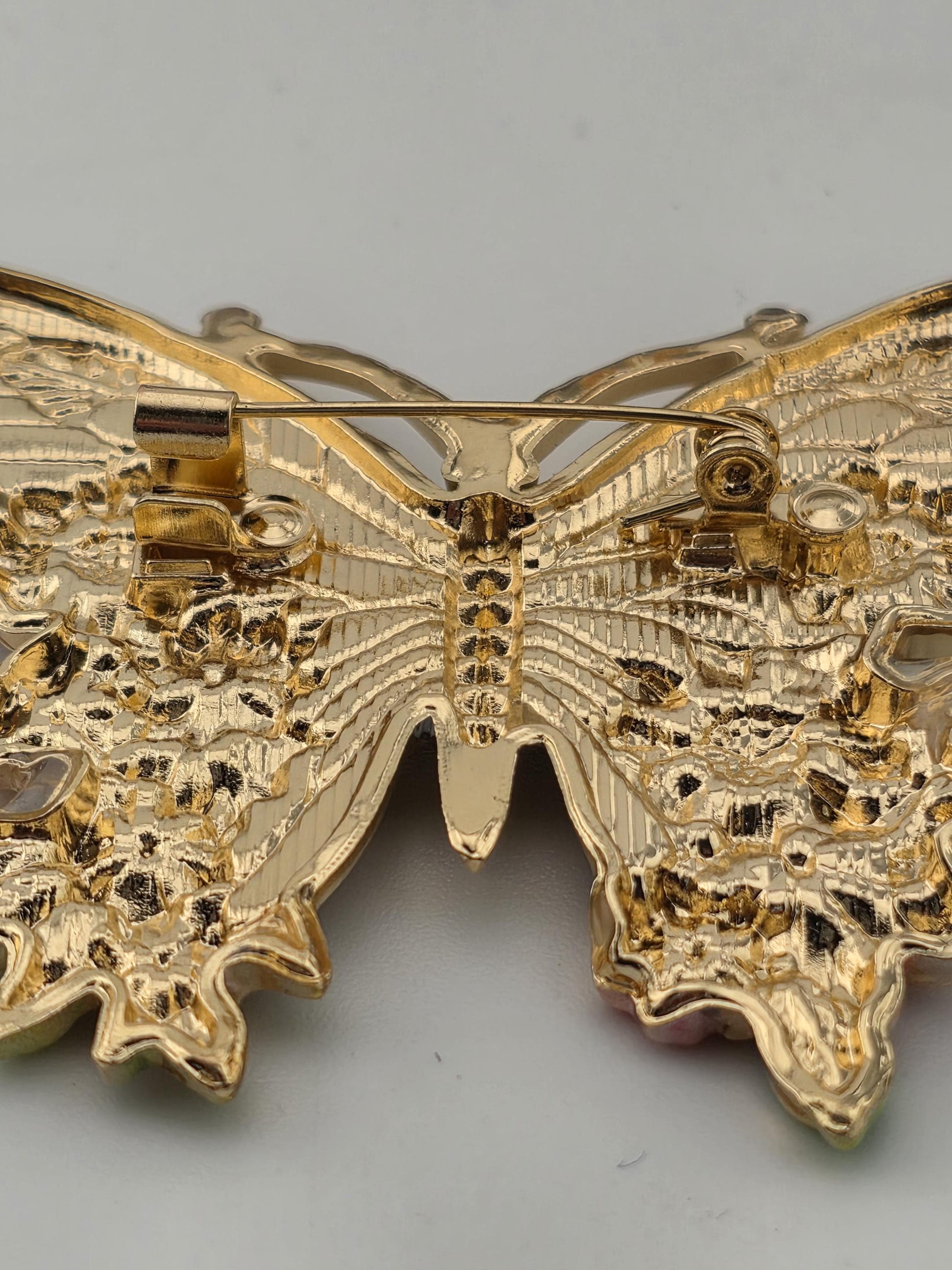 a close-up view of a golden, intricately designed butterfly brooch.