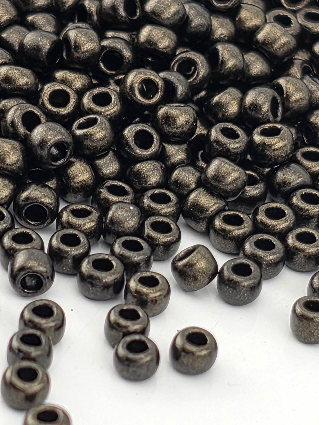 a close-up view of numerous small, shiny metal beads scattered across a white surface.