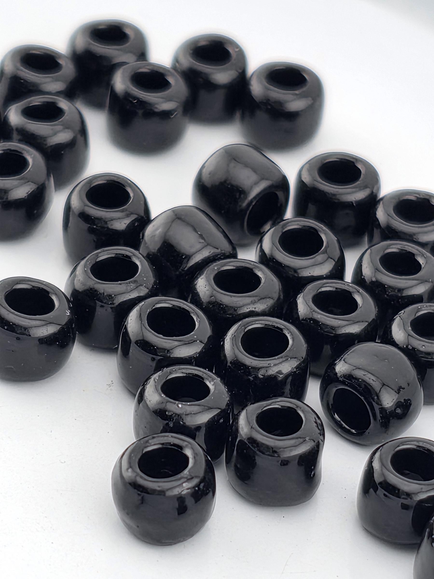 A collection of black beads or objects with a shiny, reflective surface, arranged in a scattered pattern on a white background.