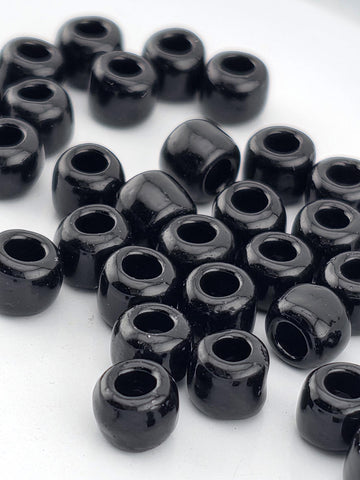 A collection of black beads or objects with a shiny, reflective surface, arranged in a scattered pattern on a white background.