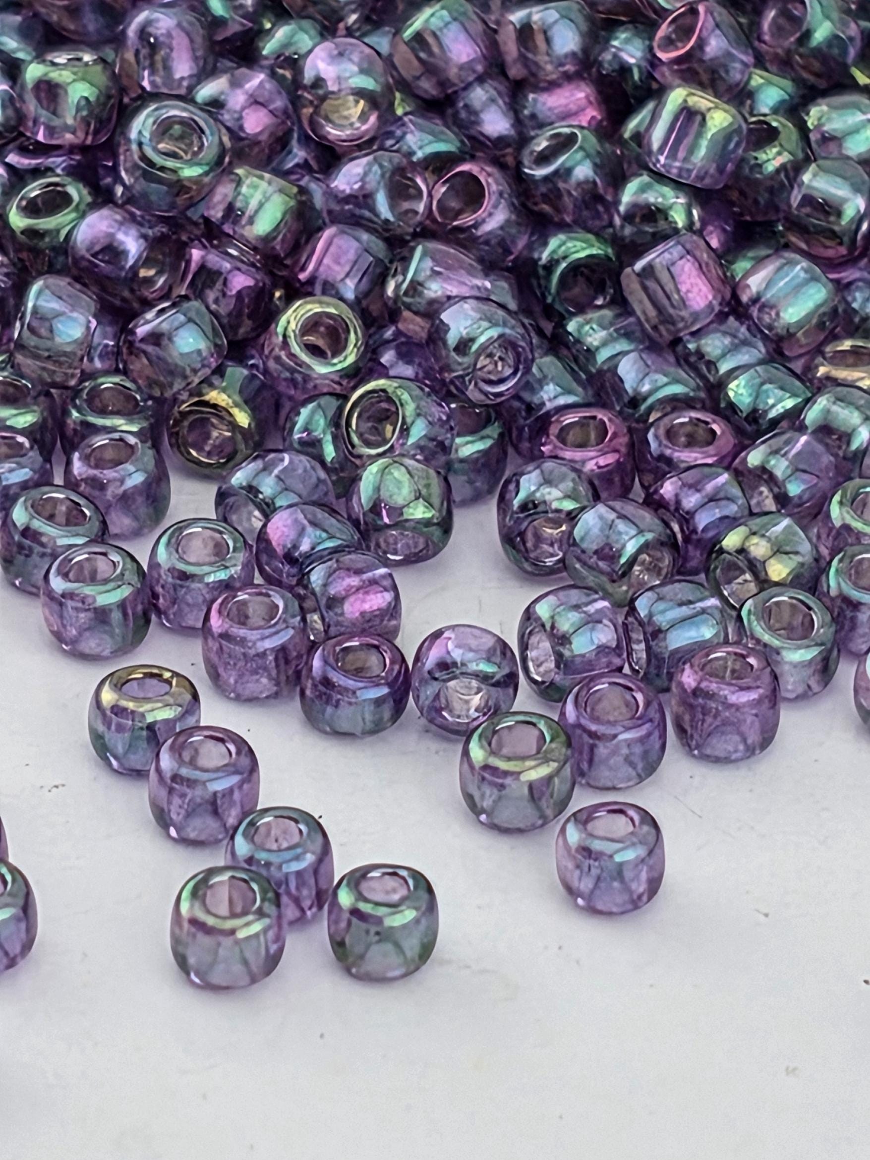 a close-up view of numerous purple glass beads scattered on a white surface.