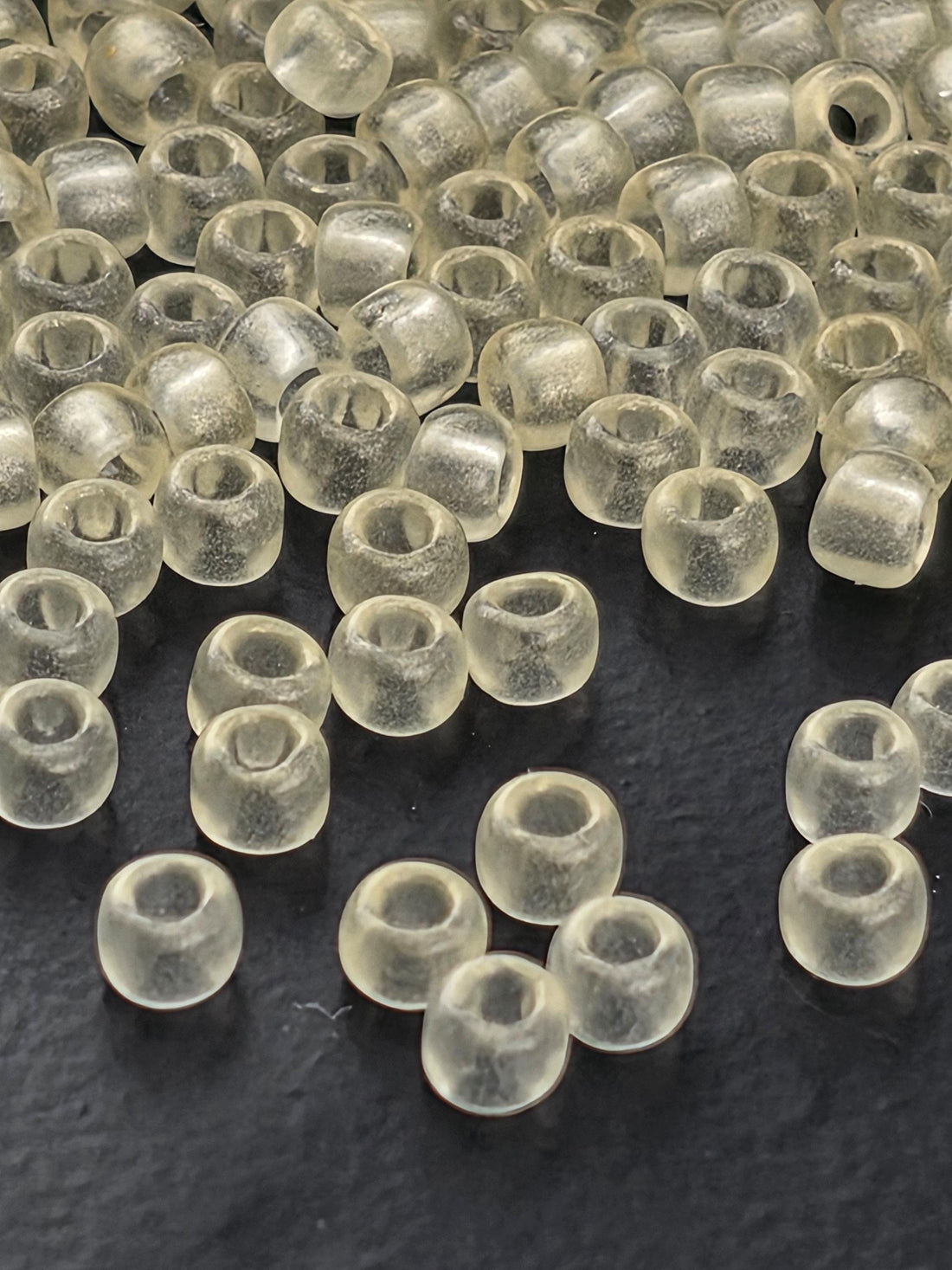 a collection of clear, transparent beads scattered on a dark surface.