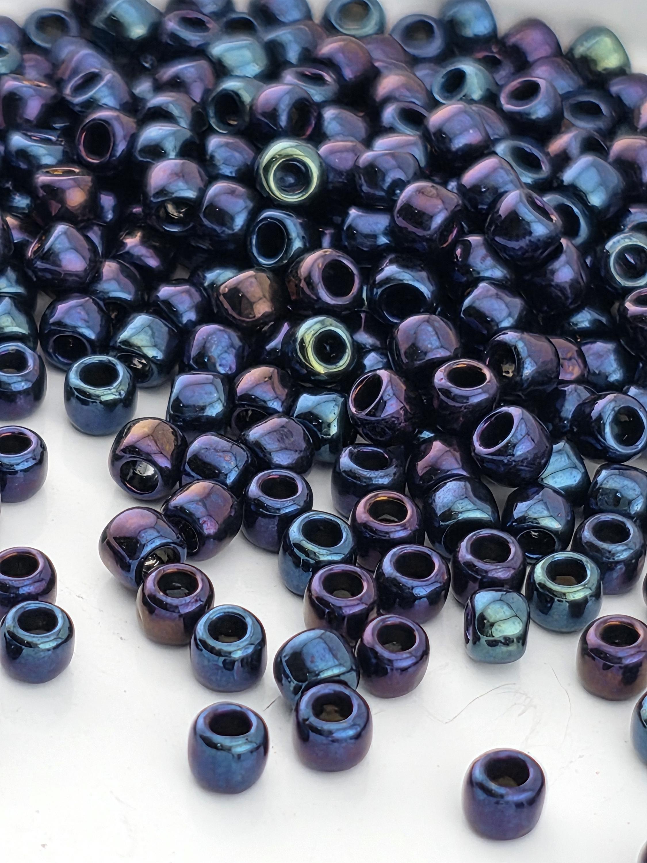 A close-up image of numerous small, round beads in shades of blue and purple, scattered on a white surface.