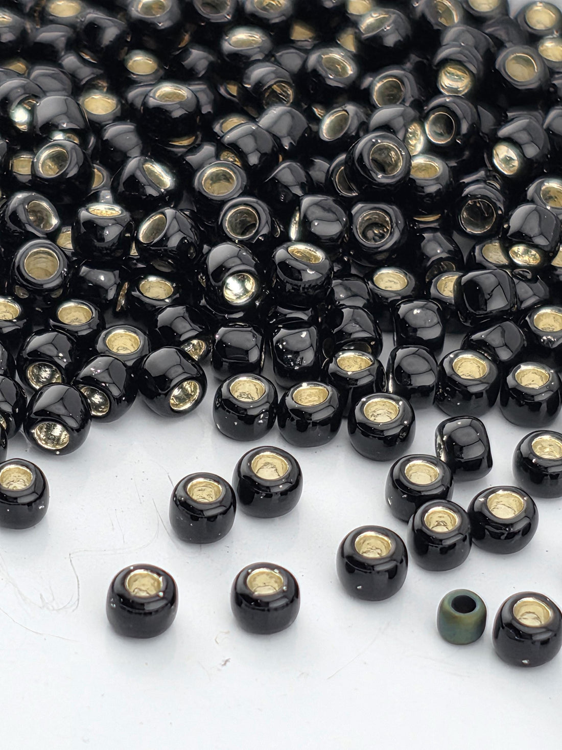 a large pile of black and gold beads scattered on a white surface.