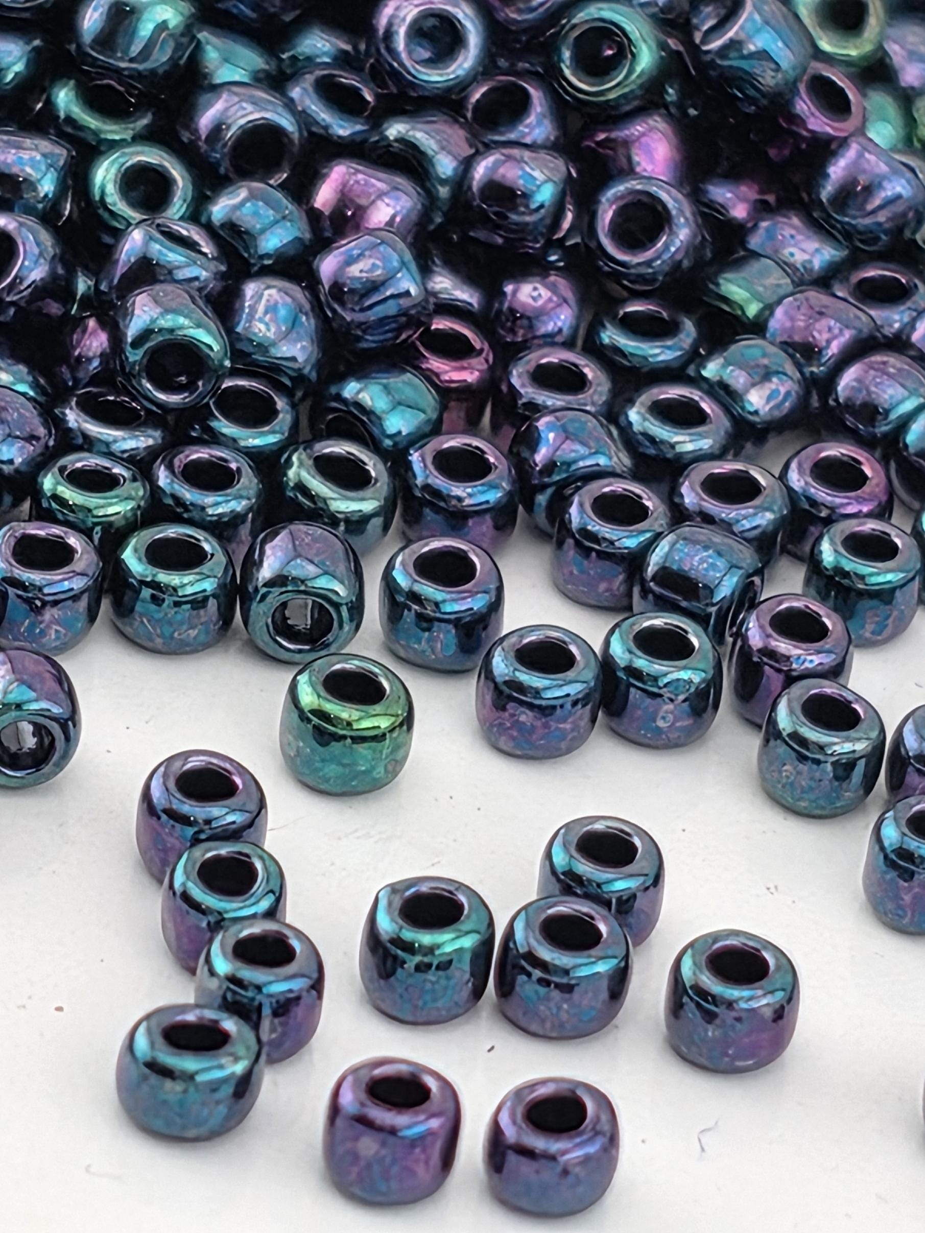 a collection of multicolored beads, including purple, green, and blue beads, scattered on a white surface.
