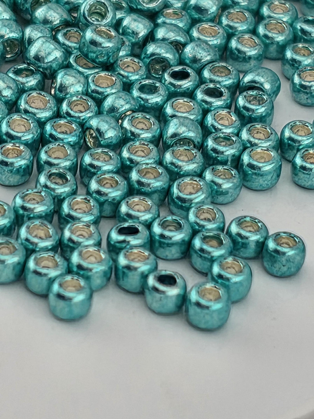 a close-up view of numerous turquoise beads or beads with a metallic sheen, scattered across a surface.