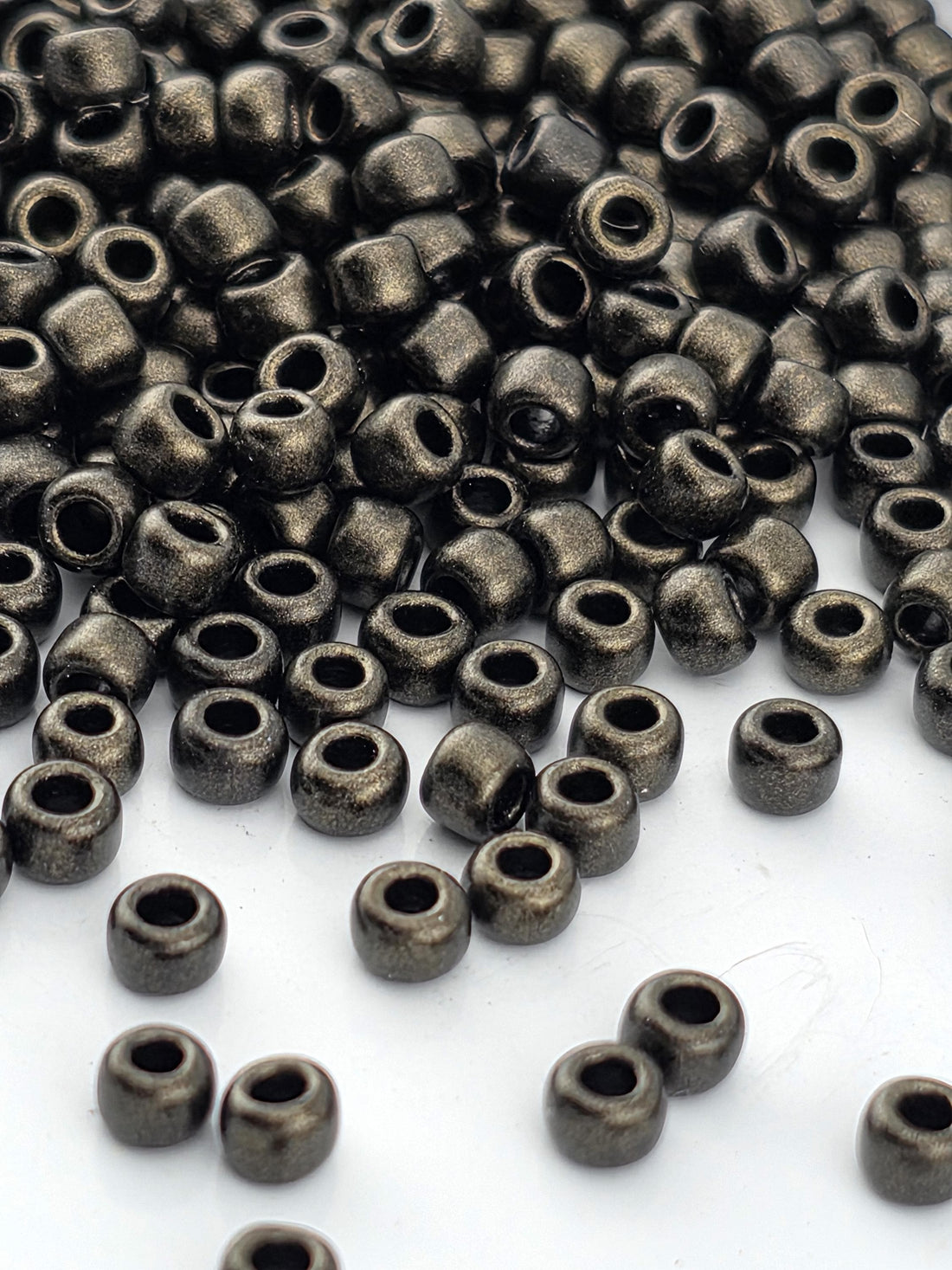 A close-up image of numerous small, shiny metal beads scattered on a white surface.