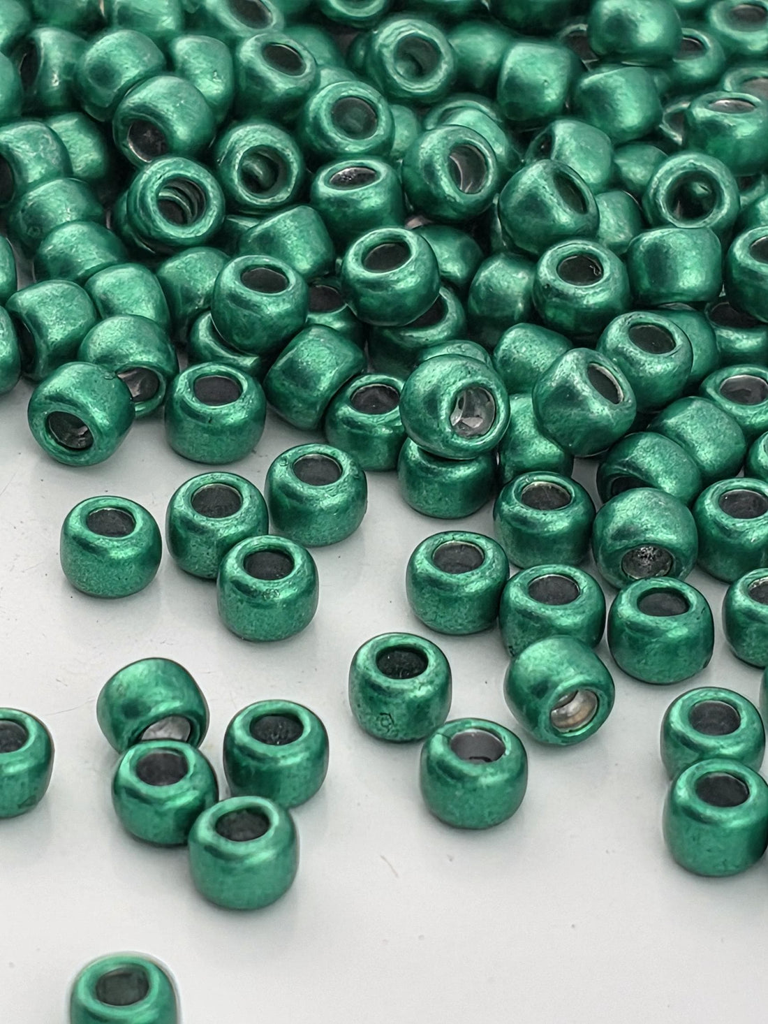 a collection of green beads scattered across a white surface.