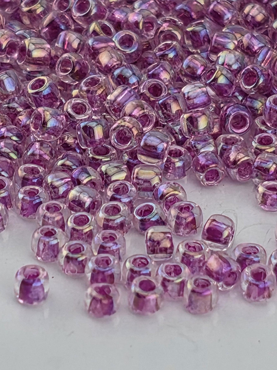 a close-up view of numerous small, clear beads in shades of purple, scattered across a surface.