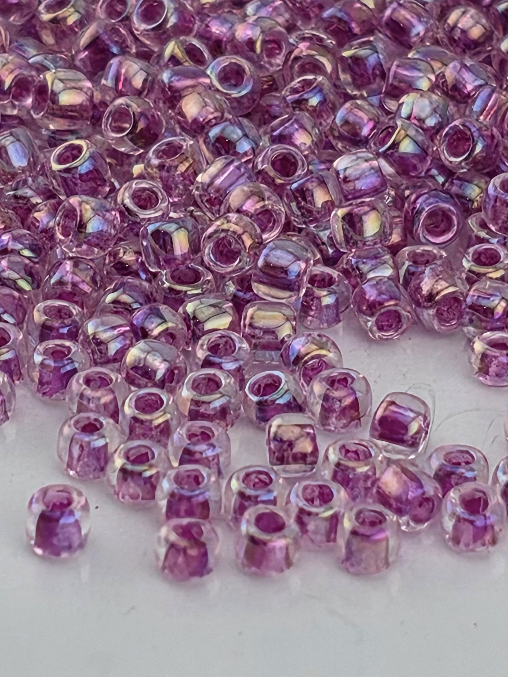 a close-up view of numerous small, clear beads in shades of purple, scattered across a surface.