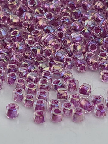 a close-up view of numerous small, clear beads in shades of purple, scattered across a surface.