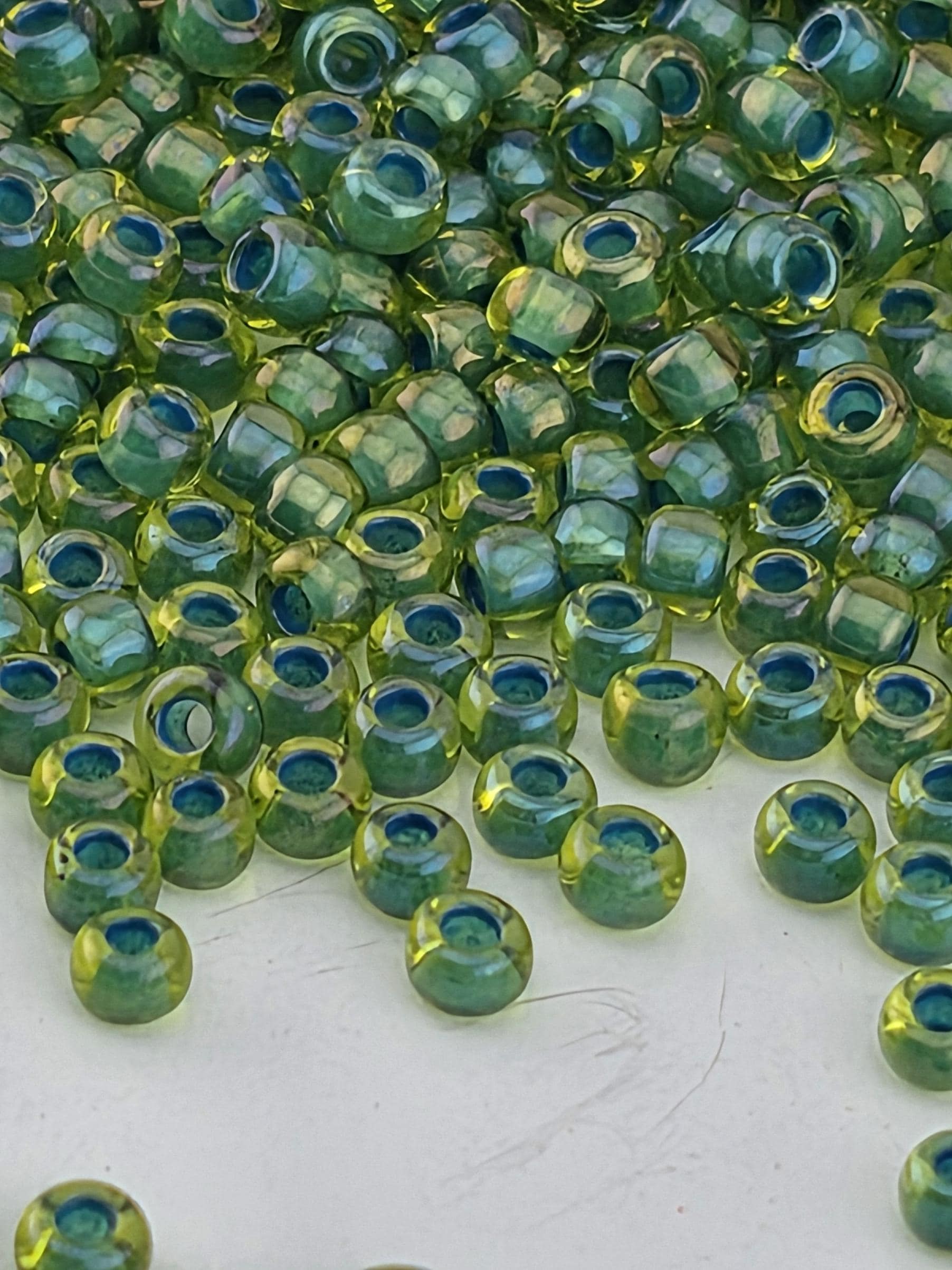 a close-up view of numerous green and yellow beads scattered across a white surface.