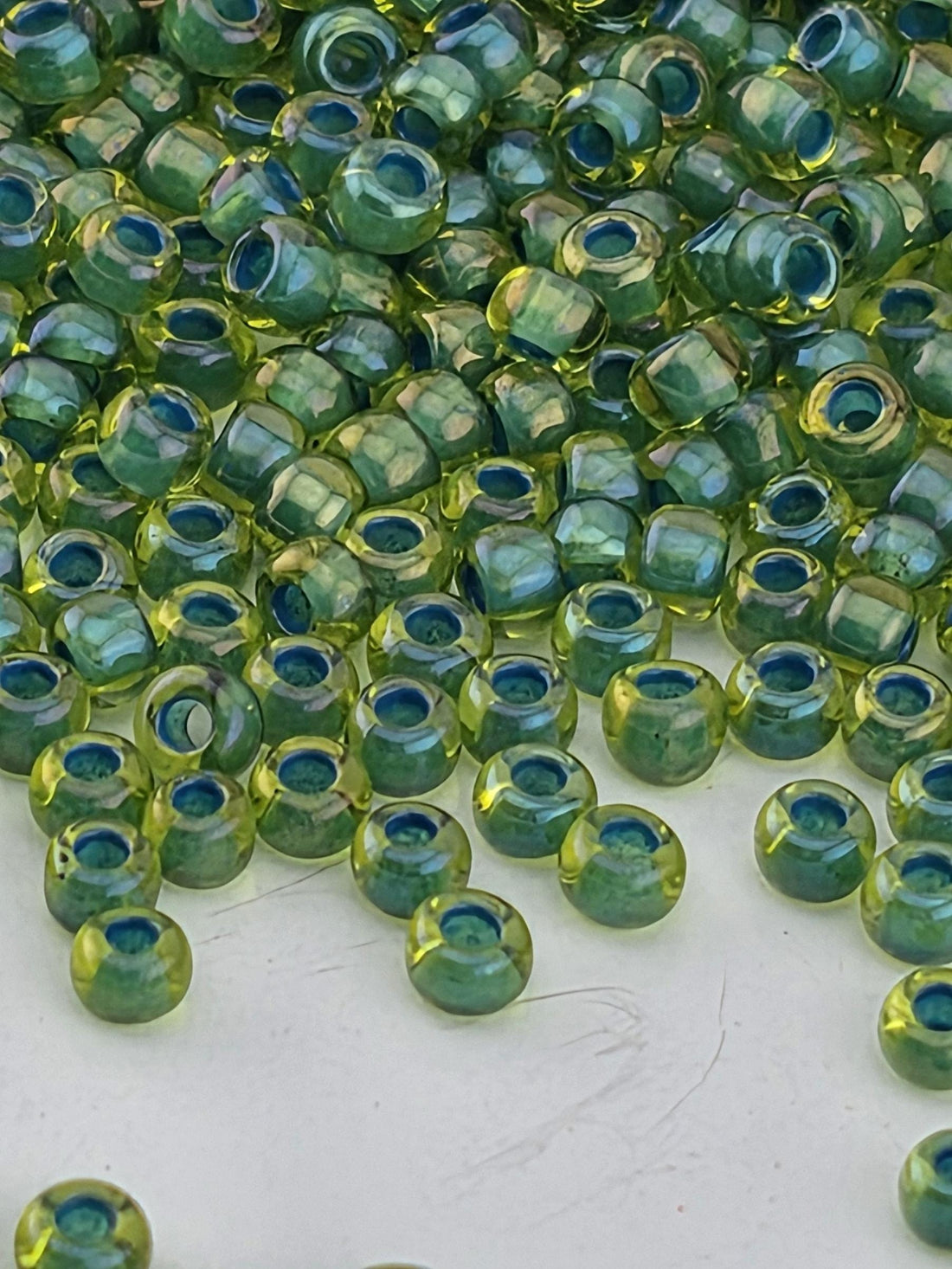 a close-up view of numerous green and yellow beads scattered across a white surface.