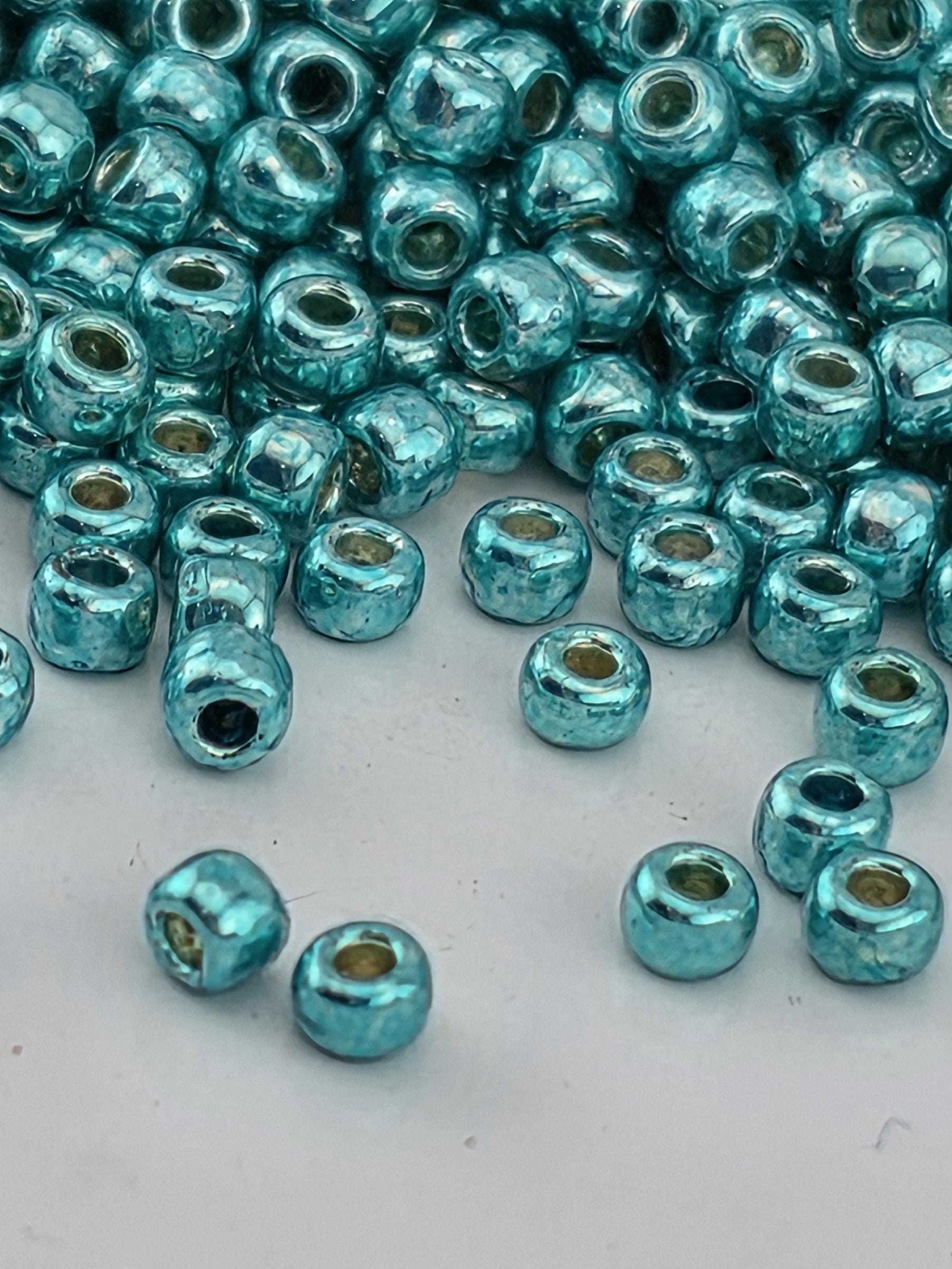 a collection of small, shiny blue beads scattered on a white surface.