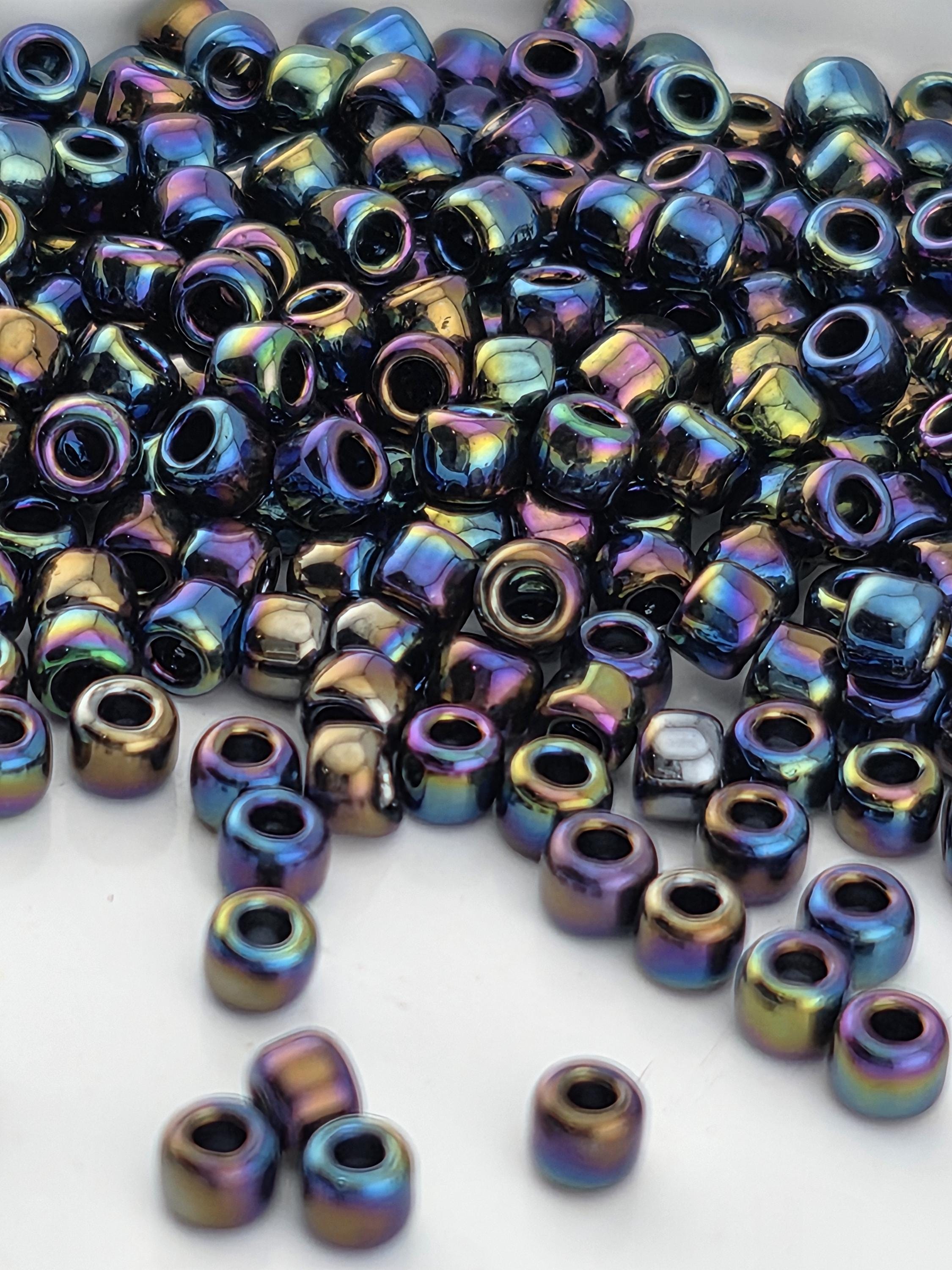 a close-up view of a pile of multicolored glass beads, with various shades of blue, purple, green, and yellow. The beads are scattered and overlapping, creating a visually striking and vibrant display.