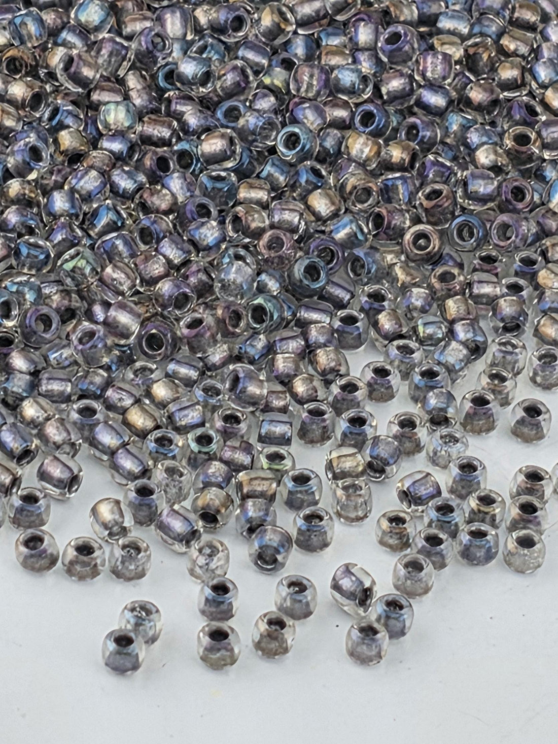 a large pile of multicolored glass beads scattered on a white surface.