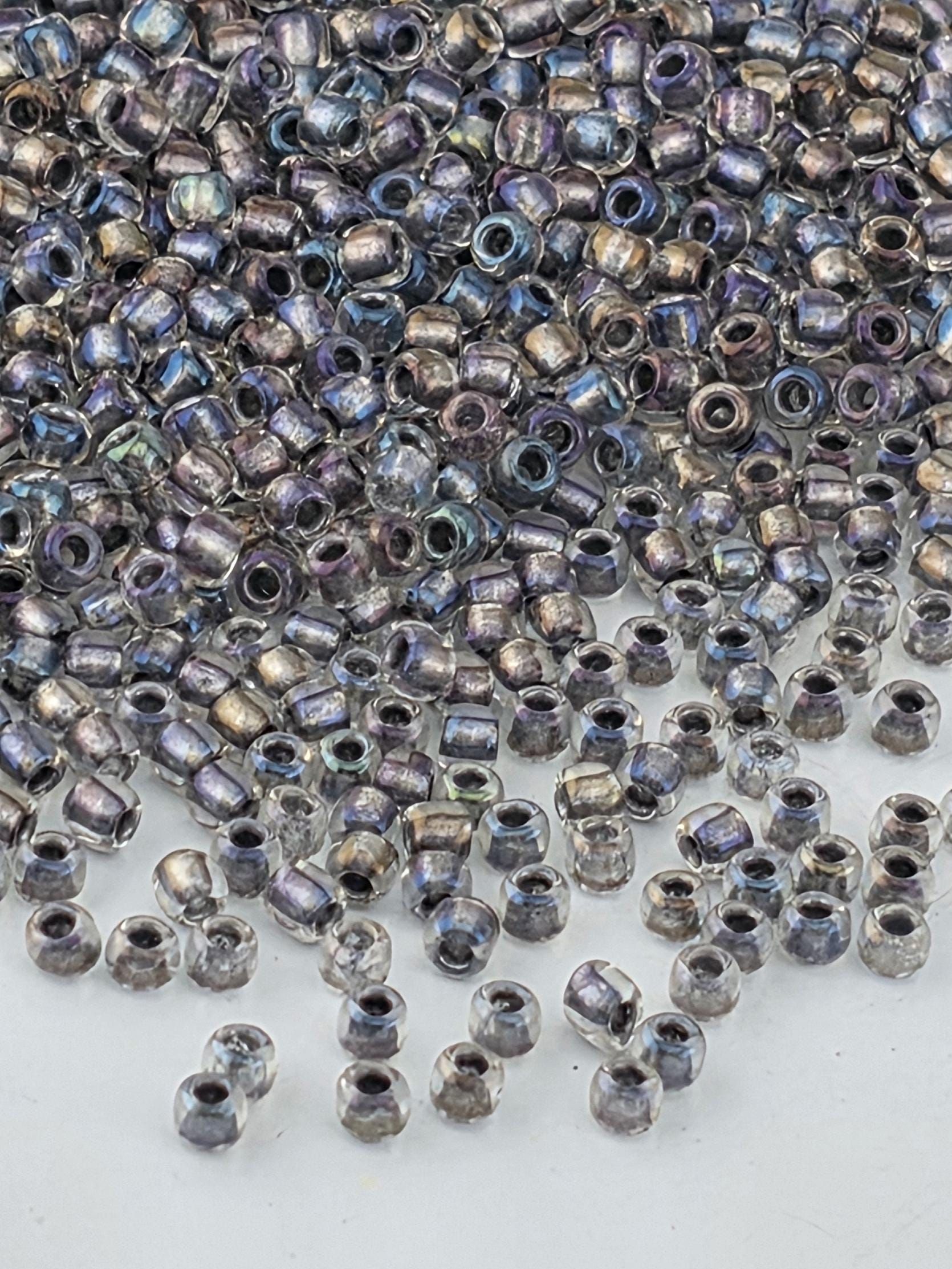 a large pile of multicolored glass beads scattered on a white surface.