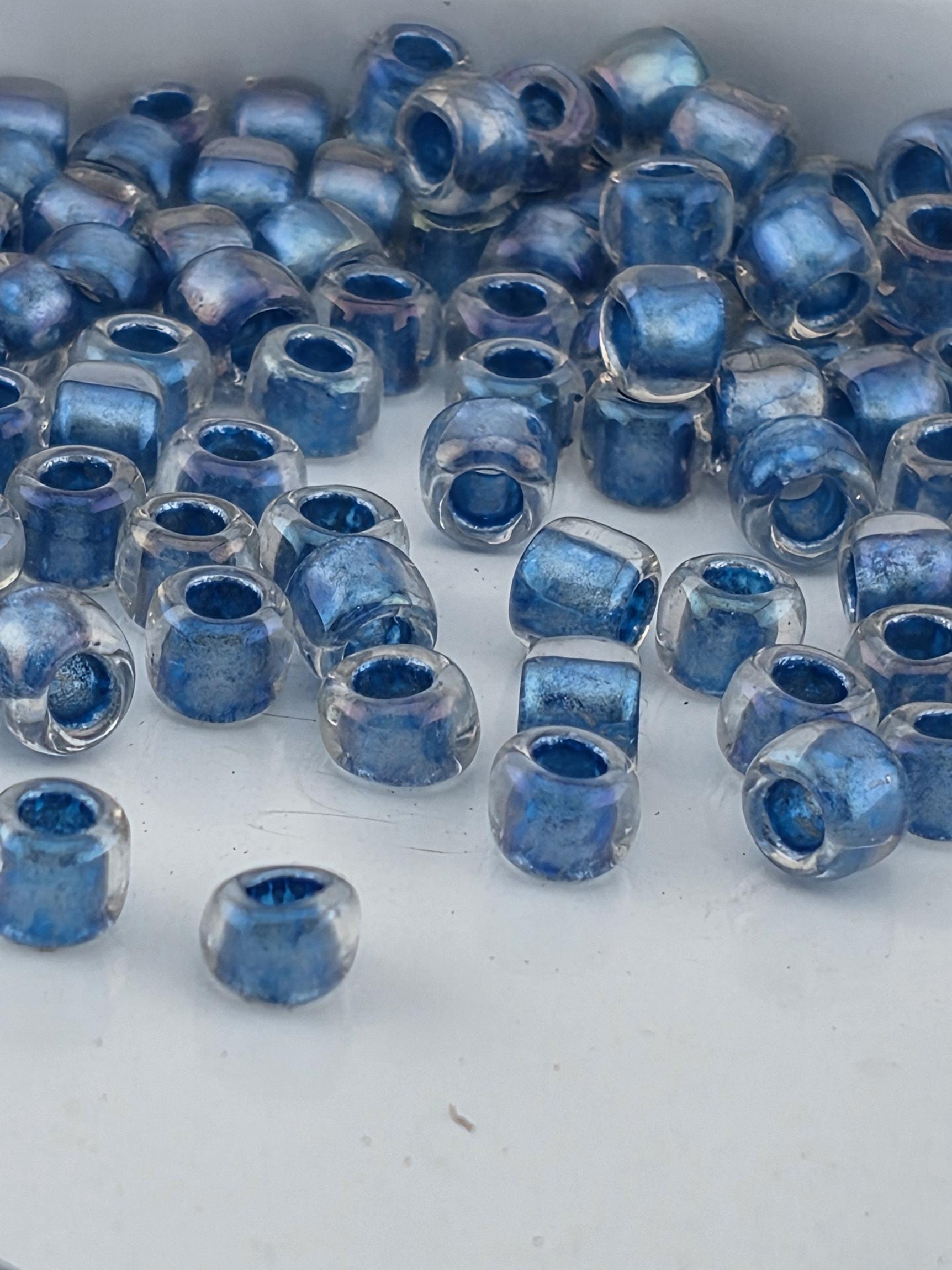 a collection of clear glass beads in various shades of blue, scattered on a white surface.