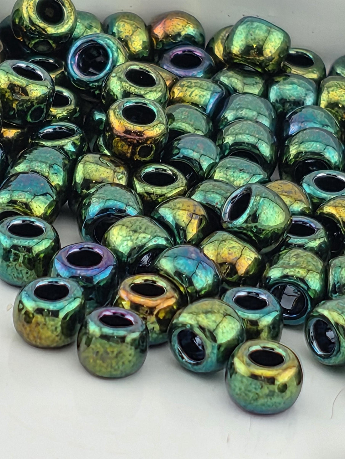 a close-up view of a pile of multicolored glass beads, with various shades of green, blue, and purple.