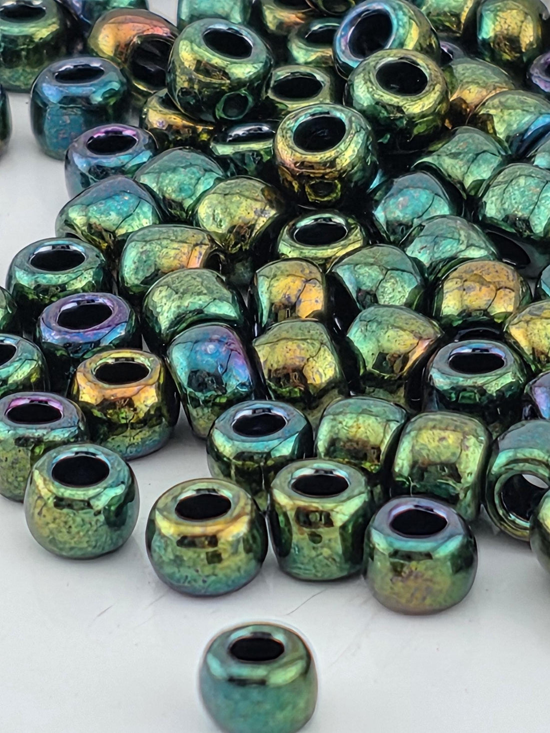 a close-up view of a pile of multicolored glass beads, with various shades of green, blue, and purple.