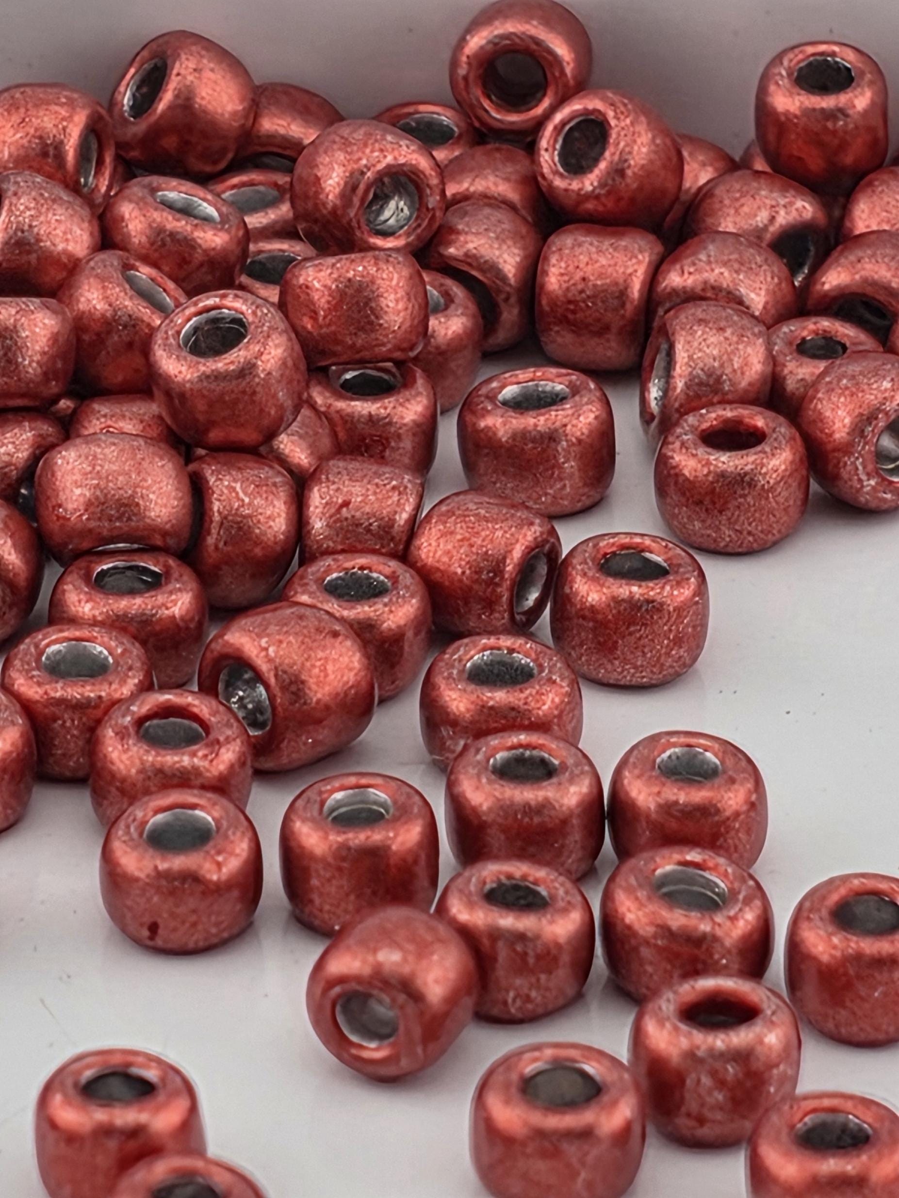 a collection of red metal beads scattered on a white surface.