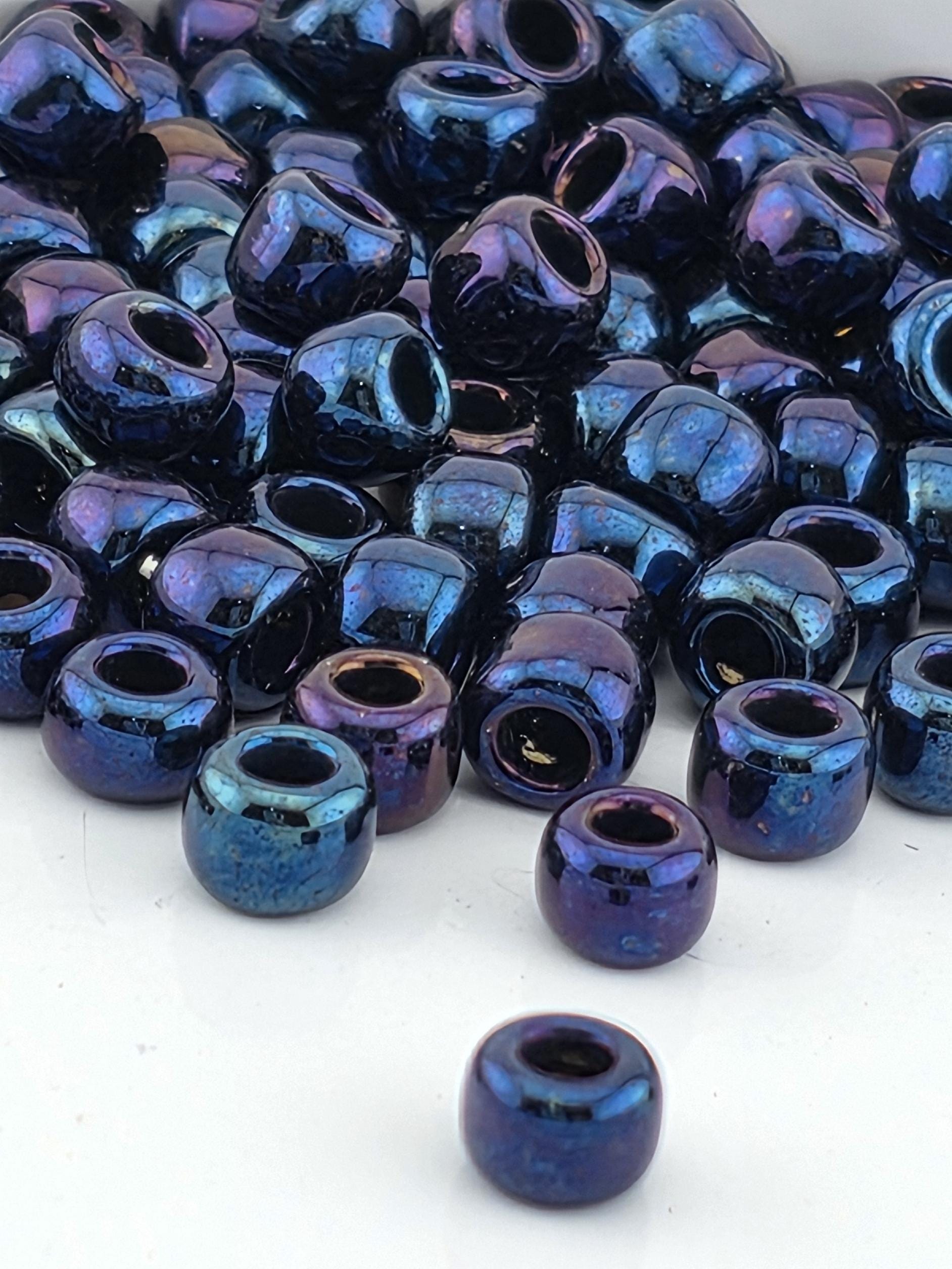 a collection of multicolored glass beads, including blue, purple, and black, scattered on a white surface.
