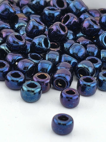 a collection of multicolored glass beads, including blue, purple, and black, scattered on a white surface.
