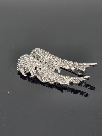 A silver brooch with sparkling rhinestones, resembling a pair of angel wings.