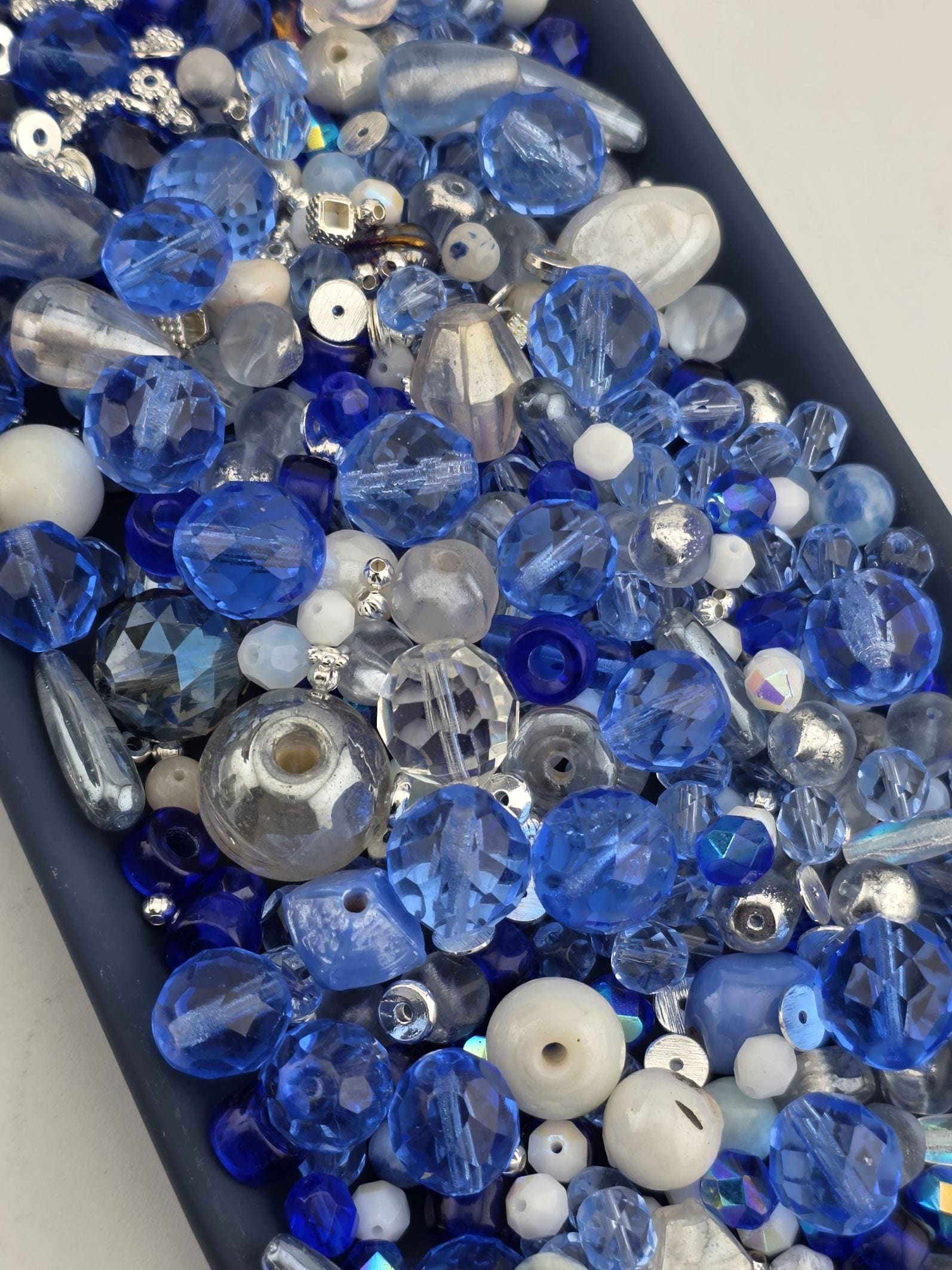 A collection of various blue and silver beads, including clear, white, and multicolored beads, arranged in a visually appealing manner.